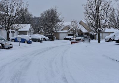 Snow covered cars on road against sky