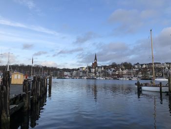 Sailboats in river by buildings against sky in city