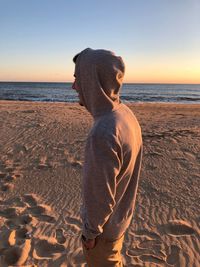 Man standing on beach against sky during sunset