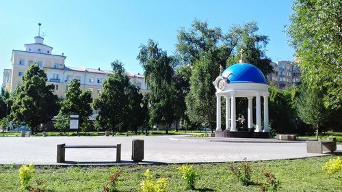 Built structure by trees against blue sky