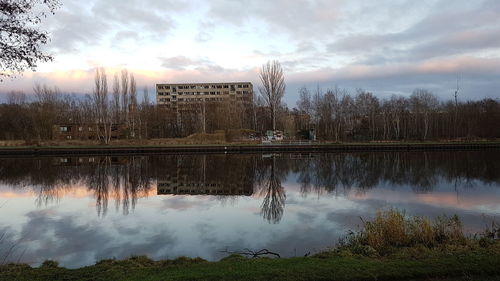 Reflection of trees in lake against cloudy sky