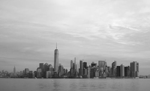 View of city at waterfront against cloudy sky