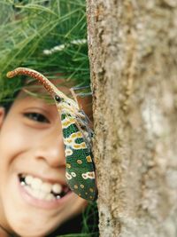 Close-up portrait of smiling girl against tree trunk
