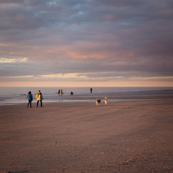 People on beach against sky during sunset