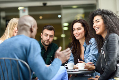 Friends talking while sitting at outdoor cafe