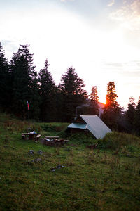 Tent in field against sky during sunset