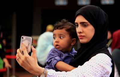 Close-up of mother taking selfie with toddler son in city