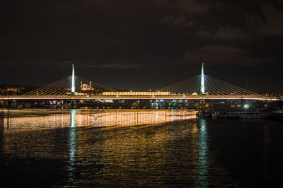 Illuminated suspension bridge over river at night