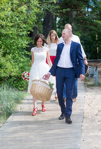 Newlywed couple walking with friends on wooden paneling