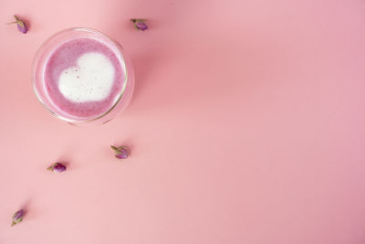 Pink rose milk with rose petals. heart-shaped foam in a glass of moon milk. healthy drink.