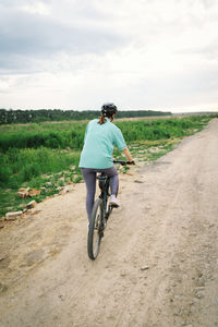 Rear view of man riding bicycle on road