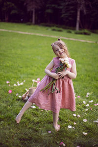 A child girl in a dress holds a bouquet of peonies in her hands on a green meadow