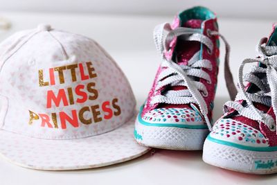 Close-up of little miss princess text on cap and shoes on table