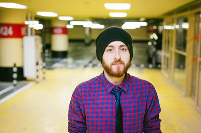 Close-up portrait of young man standing in illuminated parking garage