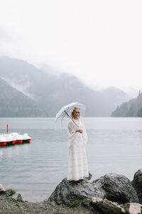 Woman standing in lake against mountains