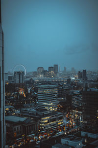 Illuminated cityscape against sky at dusk