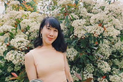 Portrait of young woman standing amidst plants