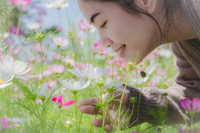 Close-up of young woman with flowering plant on field