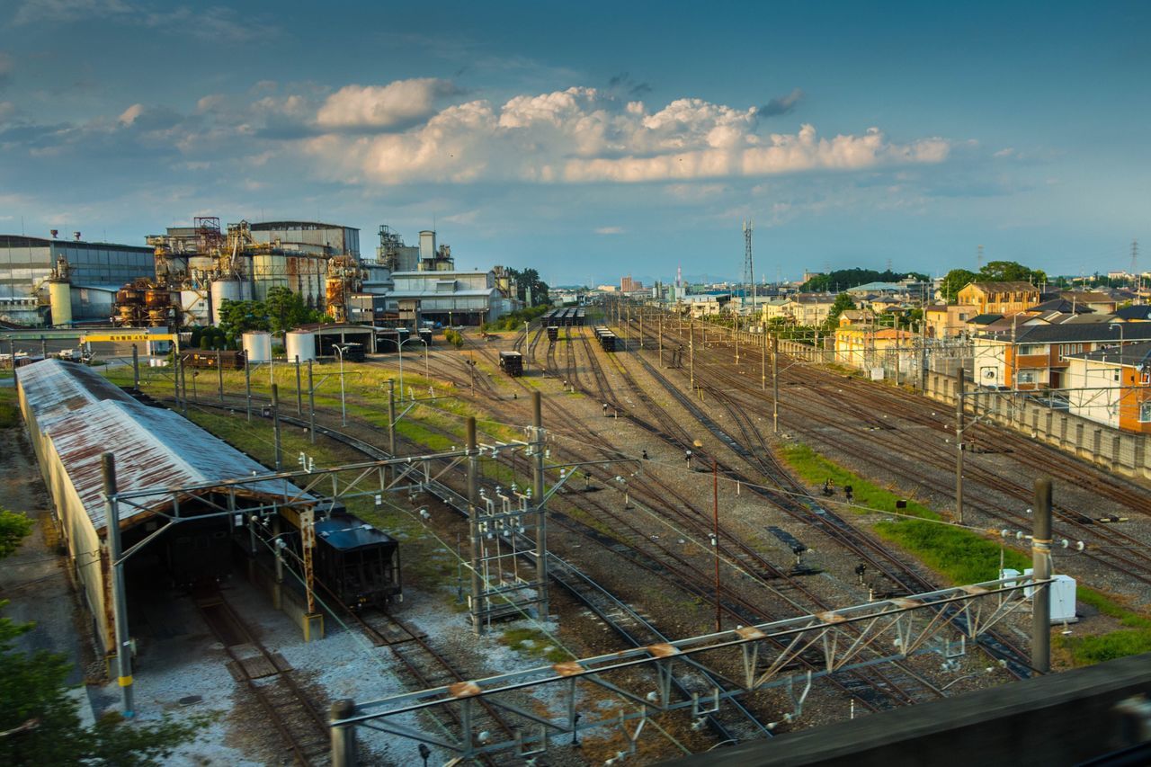 building exterior, architecture, built structure, transportation, sky, high angle view, railroad track, water, city, rail transportation, mode of transport, residential building, house, residential structure, cloud - sky, day, canal, outdoors, public transportation, residential district