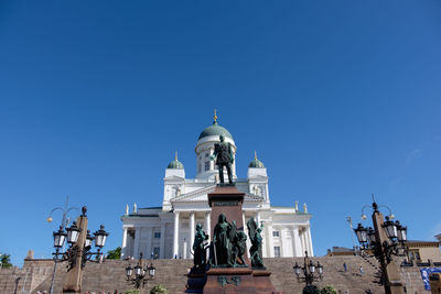 Low angle view of statue against building against clear blue sky