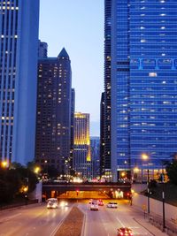 City street and modern buildings against sky at dusk