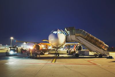 Airplane on airport runway against clear sky at night