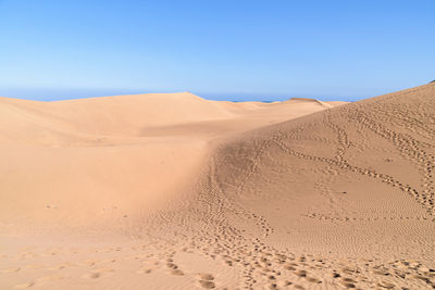 Scenic view of desert against clear blue sky