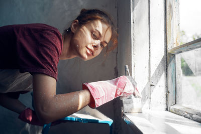 Side view of young woman looking through window