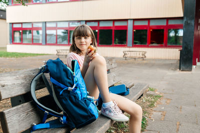 Side view of young woman sitting on bench