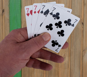 Cropped hand holding cards at wooden table