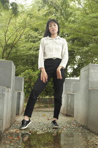 Portrait of young woman standing against trees