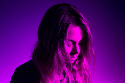 Close-up of depressed young woman against purple background