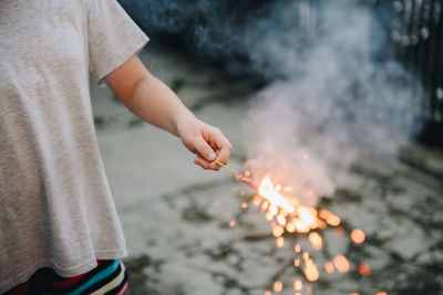 Midsection of man holding sparkler burning