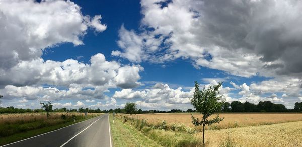 Road by field against sky
