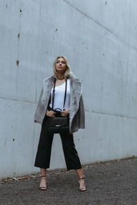 Portrait of woman standing against wall