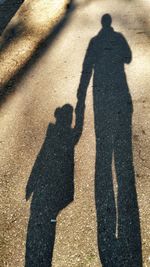 Shadow of man and woman standing on road