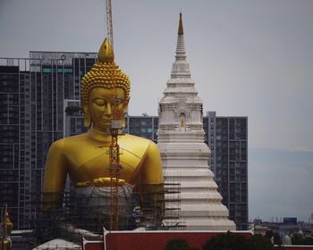 Statue amidst buildings against sky