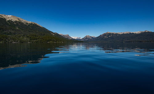 Scenic view of nahuel huapi lake by mountains against clear blue sky - villa la angostura