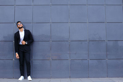 Full length of young man standing against wall