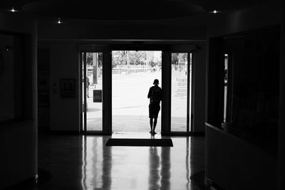 Rear view of silhouette man standing at doorway