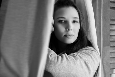 Close-up of beautiful woman looking through window at home