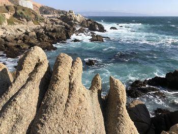 Scenic view of rocks on beach against sky