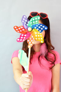 Young woman holding colorful pinwheel toy against white background 