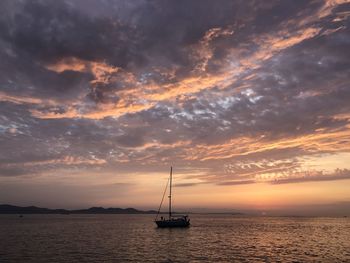 Silhouette sailboat in sea against sky during sunset