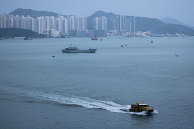 Boats in sea by buildings at city against sky