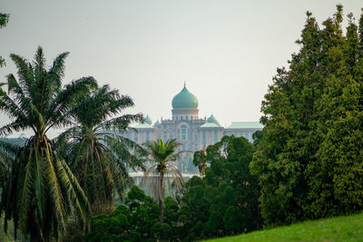Palm trees and putrajaya buildings against sky during haze in malaysia