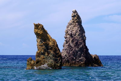 Rock formation in sea against sky