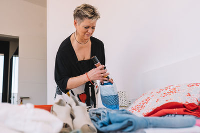 Side view of woman using mobile phone while sitting at home