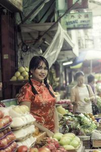 Portrait of young woman while standing by market stalls