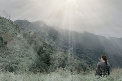 Rear view of woman on mountain during foggy weather